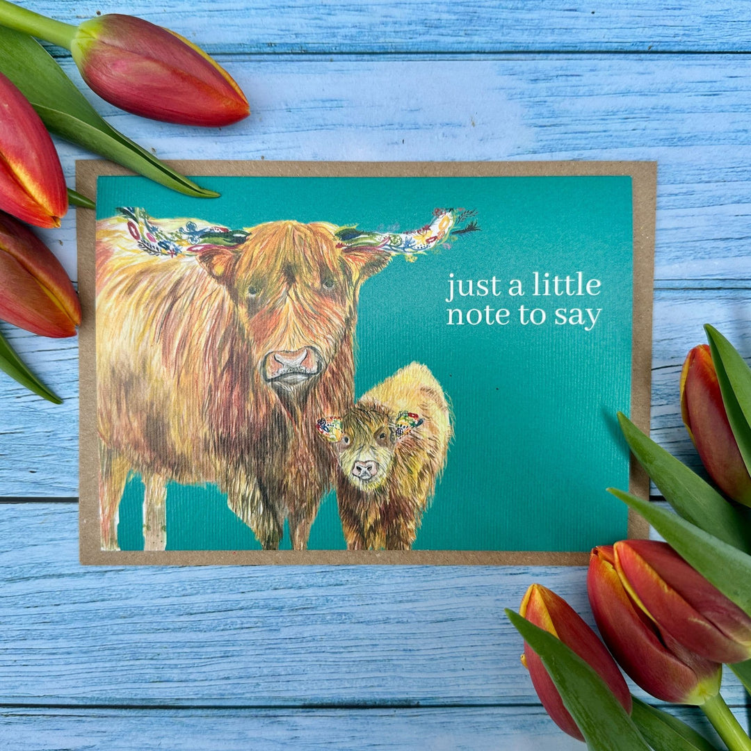 Greeting card with Highland cow illustration and tulips on a wooden surface